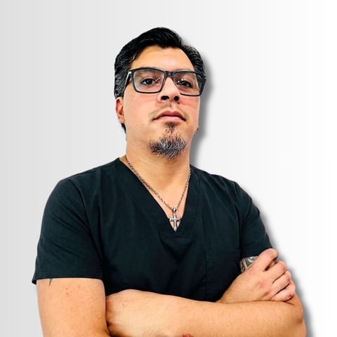Man with glasses and goatee wearing a black v-neck shirt, arms crossed, against a white background
